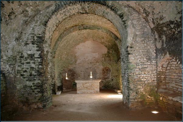La chapelle castrale.  L'abside de cette chapelle fut percée, probablement au XVe siècle, de trois archères canonnières à croisillon..