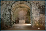 La chapelle castrale.  L'abside de cette chapelle fut percée, probablement au XVe siècle, de trois archères canonnières à croisillon..